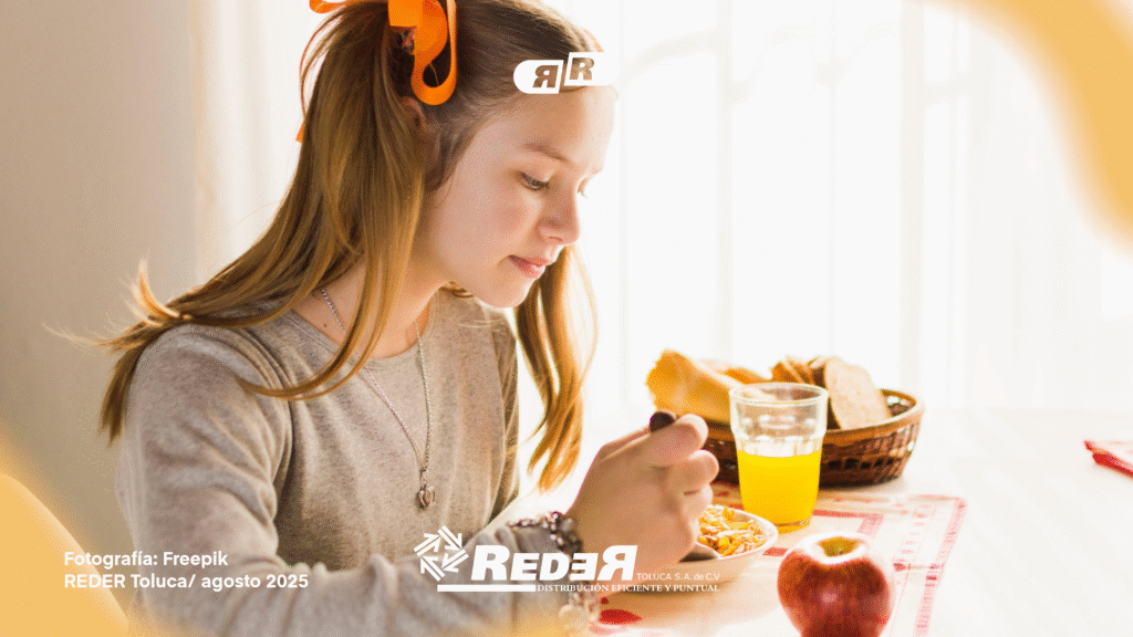 Niño desayunando fruta fresca, pan integral y leche en una mesa iluminada por luz natural